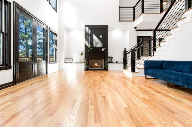 entryway with a large fireplace, a high ceiling, french doors, and hardwood / wood-style floors