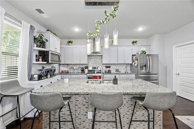 450 Noblewood Dr, Mcdonough, GA 30252 - kitchen with stainless steel appliances, wall chimney range hood, a breakfast bar area, tasteful backsplash, and decorative light fixtures
