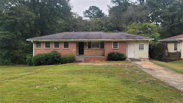 single story home with driveway, brick siding, and a front yard