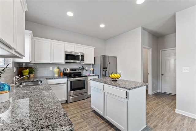 kitchen with appliances with stainless steel finishes, a center island, white cabinetry, and sink