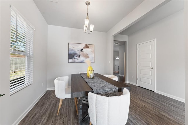 dining space with dark wood-type flooring and a notable chandelier