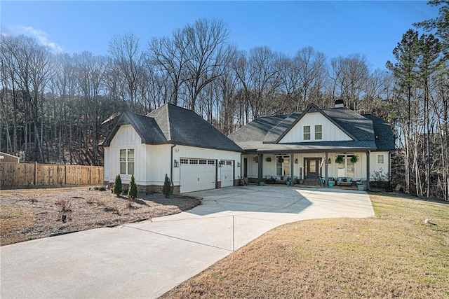 modern inspired farmhouse featuring fence, a front yard, covered porch, a garage, and driveway