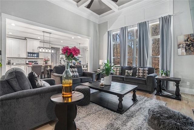 living room featuring crown molding, beam ceiling, coffered ceiling, a ceiling fan, and wood-type flooring