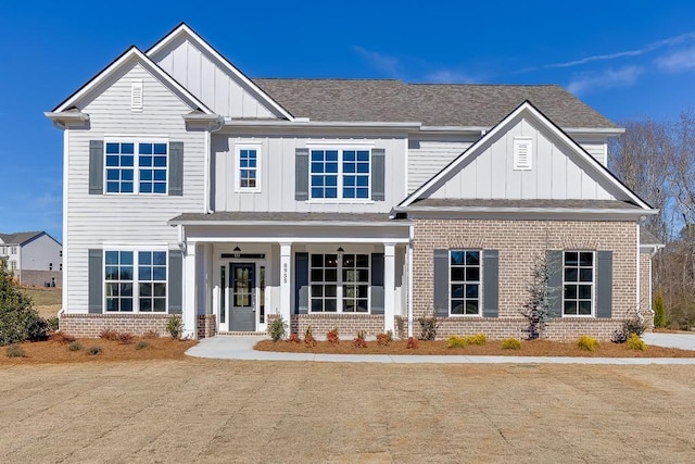 craftsman-style home featuring brick siding, board and batten siding, covered porch, and a shingled roof