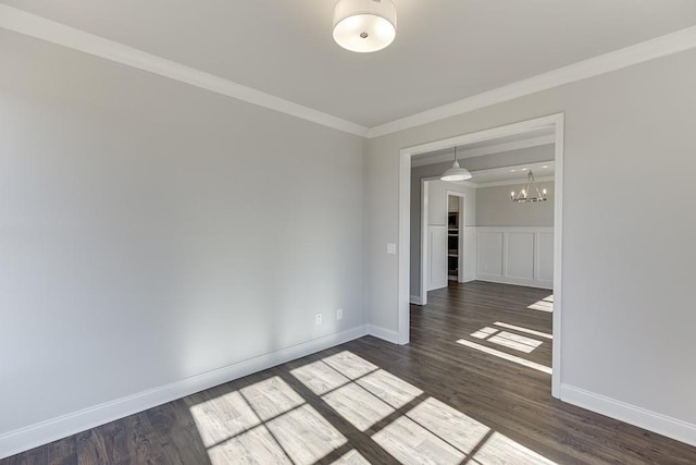 spare room featuring a wainscoted wall, crown molding, dark wood-style floors, and baseboards