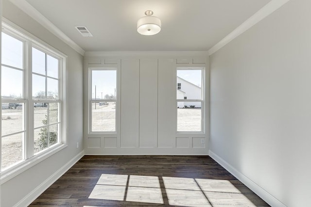 interior space with visible vents, baseboards, dark wood finished floors, ornamental molding, and a decorative wall