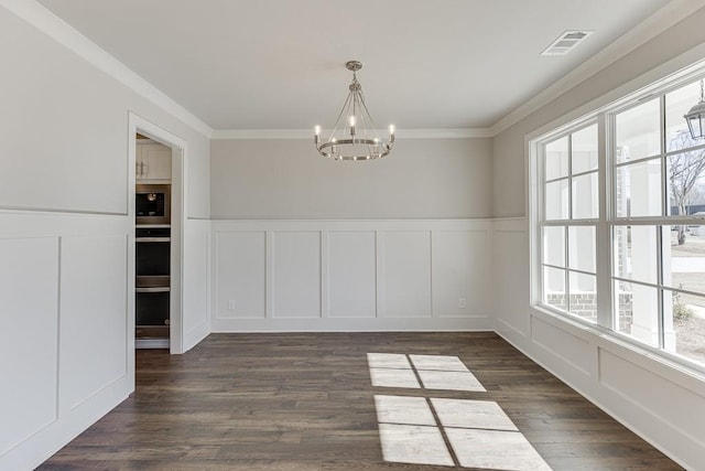 unfurnished dining area with dark wood finished floors, visible vents, crown molding, and a decorative wall