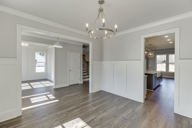 unfurnished dining area featuring a chandelier, dark wood-style flooring, and a decorative wall