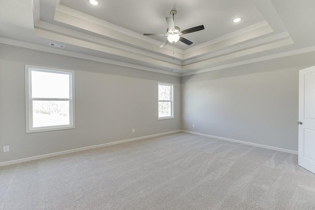 empty room with visible vents, crown molding, a raised ceiling, and baseboards