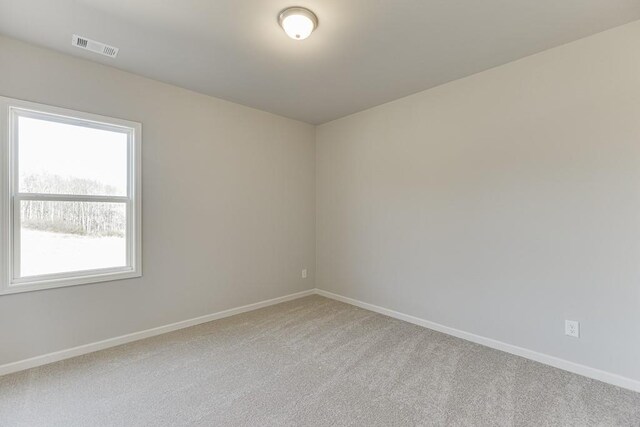 carpeted spare room with visible vents and baseboards