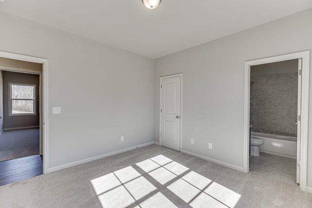 unfurnished bedroom with connected bathroom, baseboards, and carpet floors