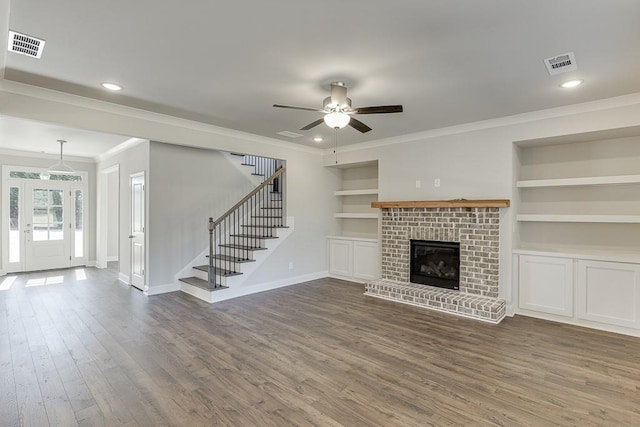 unfurnished living room featuring dark wood finished floors, visible vents, built in shelves, and stairs