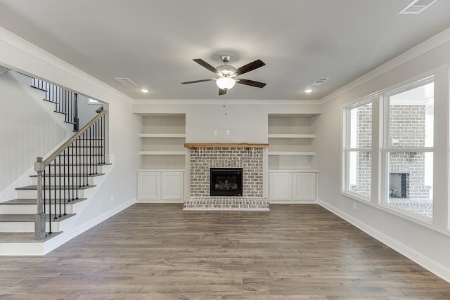 unfurnished living room with built in features, visible vents, and a brick fireplace