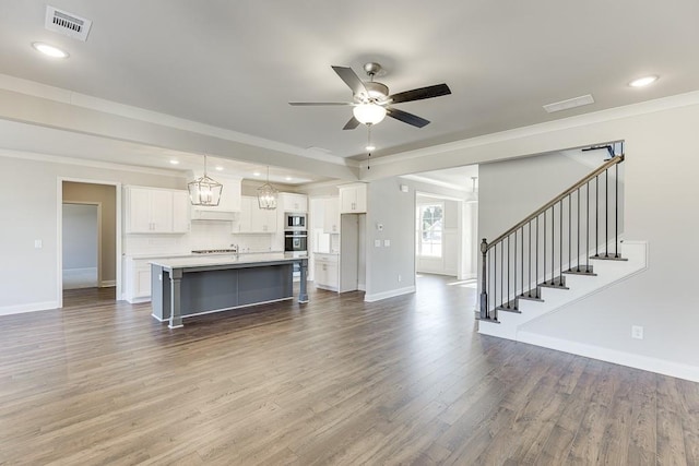 kitchen featuring ceiling fan with notable chandelier, white cabinetry, appliances with stainless steel finishes, light countertops, and dark wood-style flooring