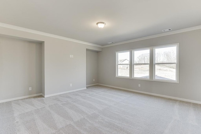 unfurnished room featuring visible vents, baseboards, light colored carpet, and ornamental molding