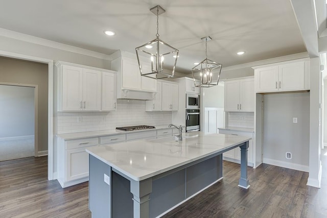 kitchen featuring dark wood-style floors, appliances with stainless steel finishes, white cabinets, and an island with sink