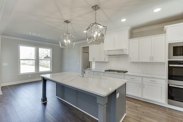 kitchen with visible vents, backsplash, ornamental molding, white cabinetry, and a sink