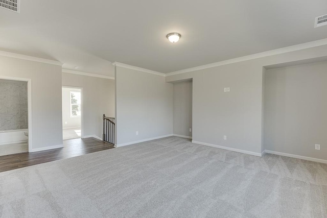 carpeted empty room featuring baseboards, visible vents, and ornamental molding