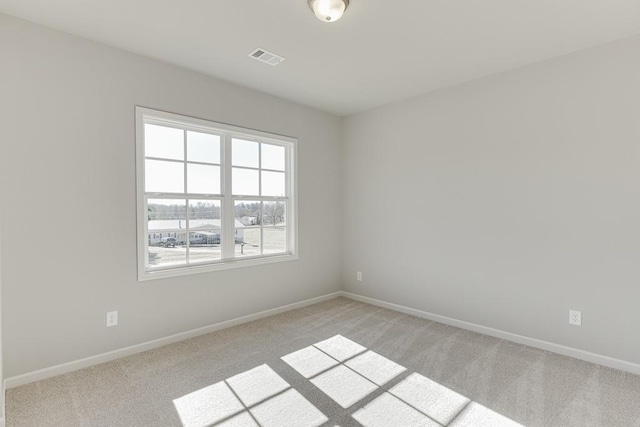 empty room featuring visible vents, baseboards, and light carpet