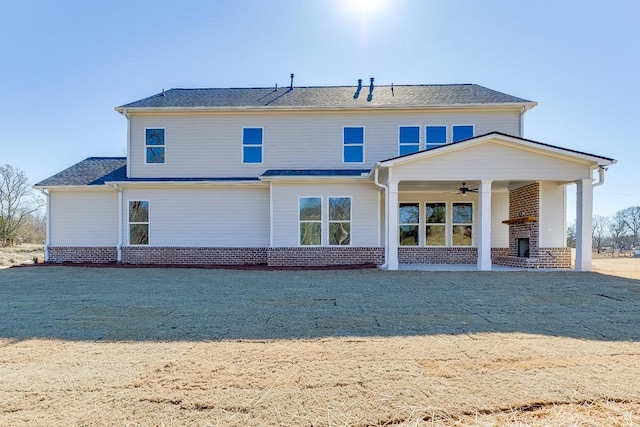 rear view of property featuring an outdoor brick fireplace, a ceiling fan, and brick siding