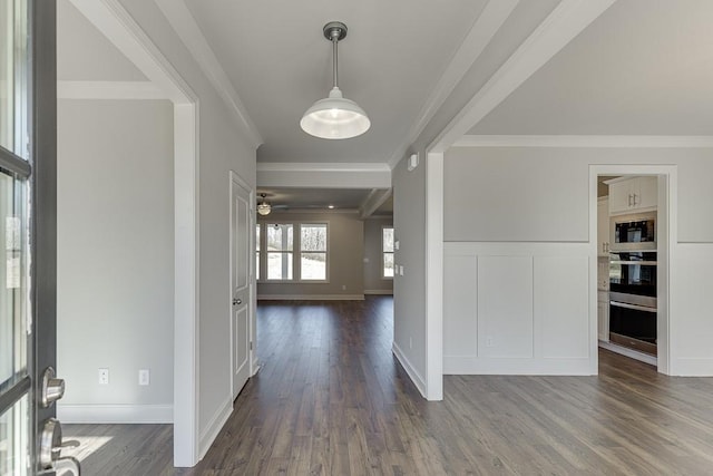 foyer entrance featuring a wainscoted wall, dark wood-style flooring, crown molding, and a decorative wall