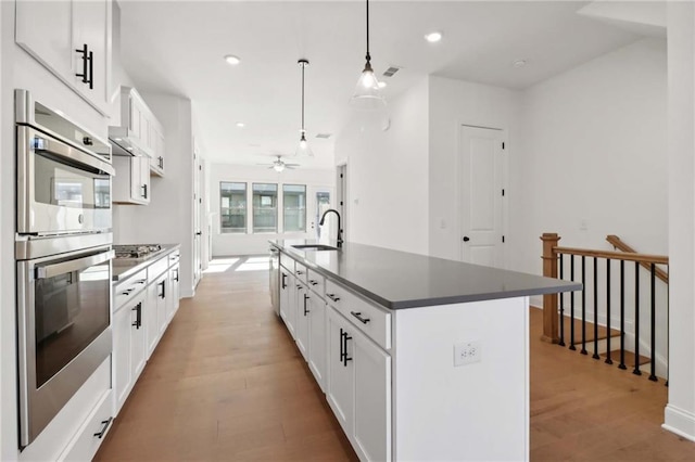 kitchen featuring pendant lighting, white cabinetry, appliances with stainless steel finishes, and an island with sink