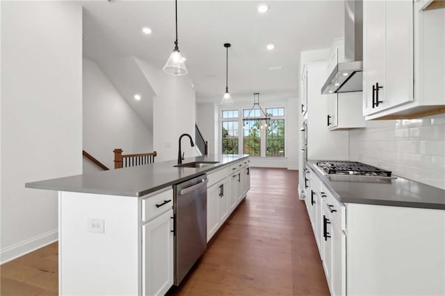 kitchen featuring appliances with stainless steel finishes, sink, white cabinets, hanging light fixtures, and a kitchen island with sink