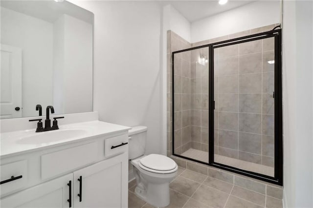 bathroom with vanity, tile patterned floors, a shower with door, and toilet