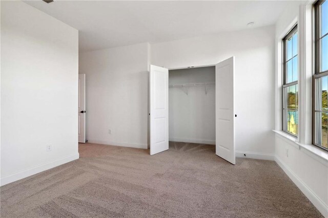 unfurnished bedroom featuring light carpet and a closet