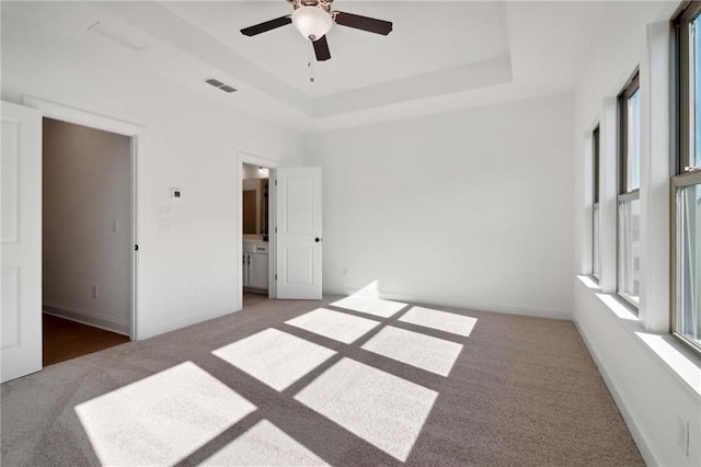 unfurnished bedroom featuring ceiling fan, carpet flooring, and a tray ceiling