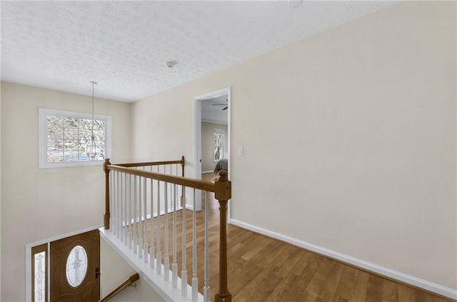 stairway featuring a textured ceiling, baseboards, and wood finished floors