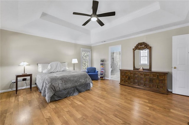 bedroom with light wood-type flooring, a raised ceiling, multiple windows, and baseboards