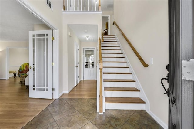 foyer with wood finished floors, visible vents, baseboards, stairs, and french doors