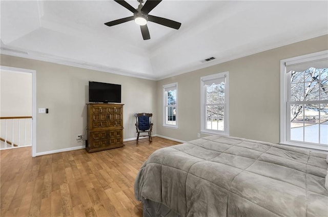 bedroom featuring a raised ceiling, visible vents, ornamental molding, wood finished floors, and baseboards