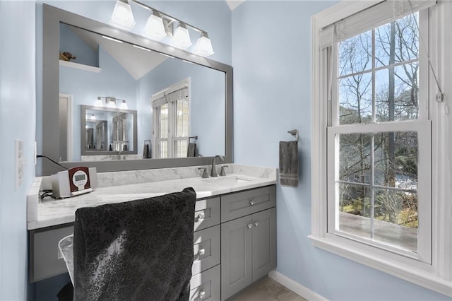 bathroom featuring lofted ceiling, baseboards, and vanity