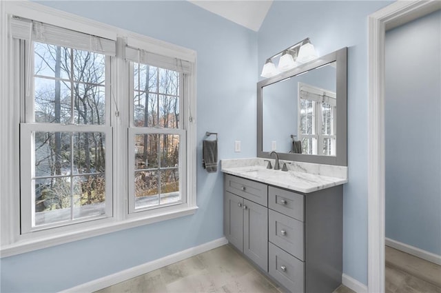 bathroom with lofted ceiling, vanity, and baseboards