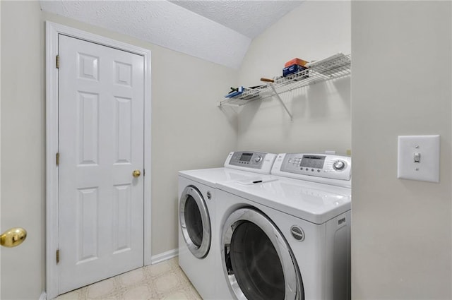 laundry area with a textured ceiling, laundry area, baseboards, light floors, and washing machine and clothes dryer