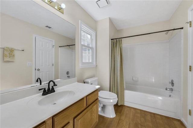 bathroom featuring visible vents, toilet, shower / bath combo with shower curtain, vanity, and wood finished floors