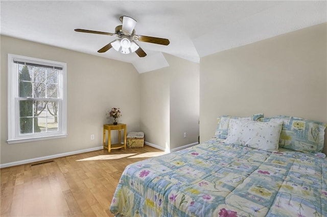 bedroom featuring lofted ceiling, ceiling fan, wood finished floors, visible vents, and baseboards