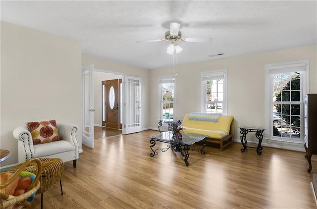 living area featuring ceiling fan, light wood-style flooring, and baseboards