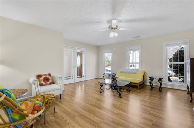 sitting room with french doors, visible vents, light wood-style floors, a textured ceiling, and baseboards