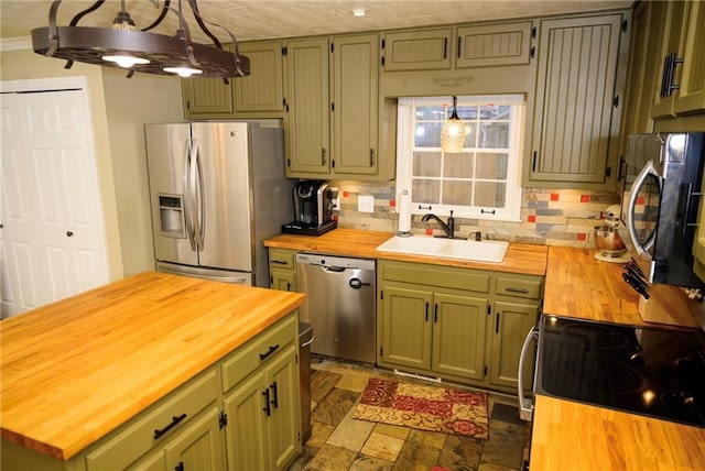 kitchen with wood counters, sink, appliances with stainless steel finishes, green cabinets, and pendant lighting