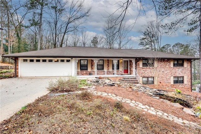 single story home with a garage, brick siding, driveway, and a porch