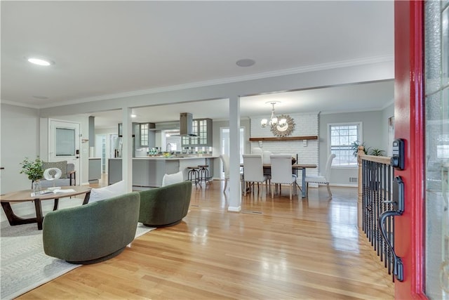 living area with light wood-style flooring, ornamental molding, a chandelier, and baseboards