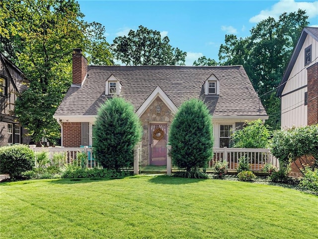 view of front facade featuring stone siding, a chimney, a front lawn, and roof with shingles