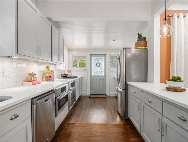 kitchen with hanging light fixtures, dark wood finished floors, stainless steel appliances, and light countertops
