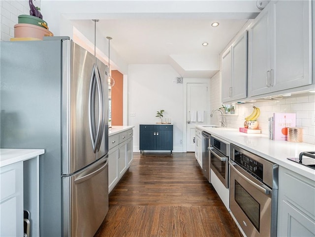 kitchen featuring dark wood-style flooring, light countertops, hanging light fixtures, appliances with stainless steel finishes, and white cabinetry