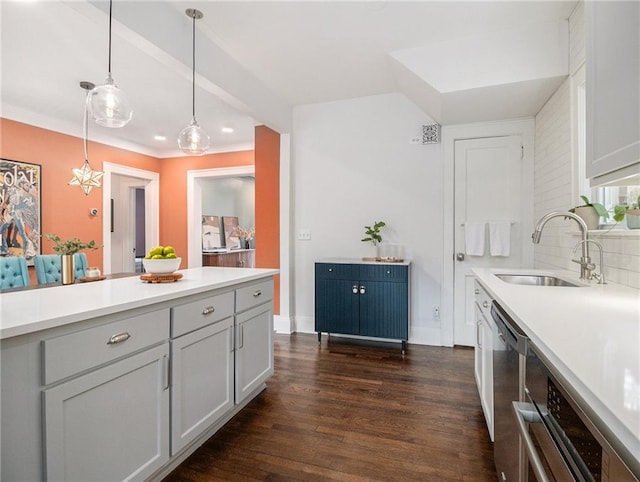 kitchen featuring dark wood-style floors, light countertops, a sink, and decorative light fixtures