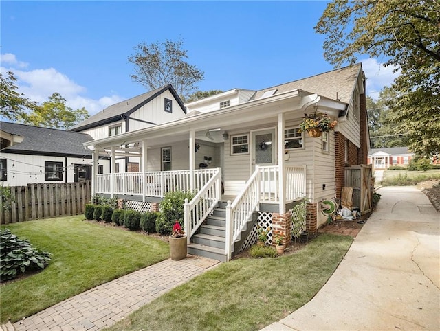 bungalow-style house with covered porch, fence, and a front yard