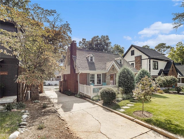view of front of house with a shingled roof, brick siding, stone siding, a front lawn, and a chimney